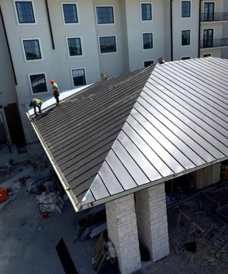 Crew installing standing seam metal roof panels on a commercial project in Ashland